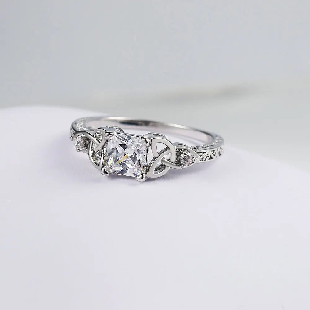 Bague avec un design en nœud et une pierre précieuse argentée au centre
