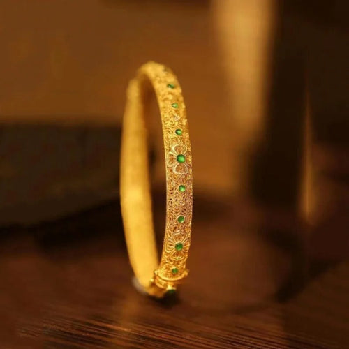 Bracelet en style jonc avec pierres précieuses vertes dorées et motif floral de style ethnique.